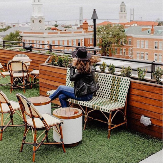 woman sitting on rattan bench on cafe rooftop